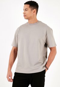 Grå t-shirt med korte ærmer lavet af blødt stof, med rund halsudskæring og en afslappet pasform, med synlige sømdetaljer.