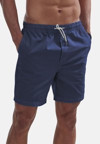 Navy blue swim shorts made from lightweight fabric, featuring an elastic waistband with drawstring and side pockets. Simple design, no patterns.