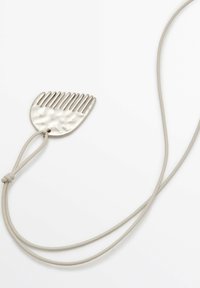 Ciondolo d'argento a forma di pettine, superficie testurizzata, su un cordino grigio chiaro. Presenta undici denti equidistanti e un attacco circolare.