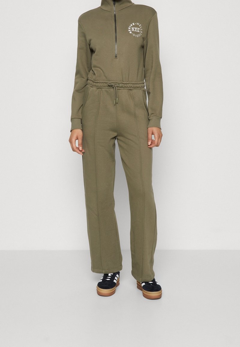 Sweatshirt zippé vert olive avec un col haut et un logo ; associé à un jogging assorti avec une taille élastique et des jambes évasées.