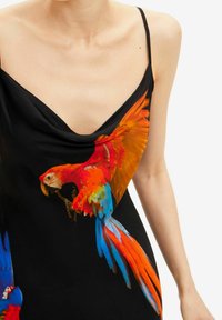 Vestito nero con scollatura profonda, decorato con grafica vivace di pappagalli arancioni, rossi e blu. Realizzato in un materiale morbido e fluido.