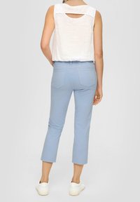 Pantalones cortos de color azul claro con una textura suave y bolsillos traseros, combinados con una blusa blanca sin mangas que presenta un corte en forma de llave en la parte posterior.
