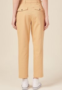 Lichtbeige katoenen broeken met een ontspannen pasvorm, voorzien van twee achterzakken met knoopsluitingen en een rechstreeks ontwerp.