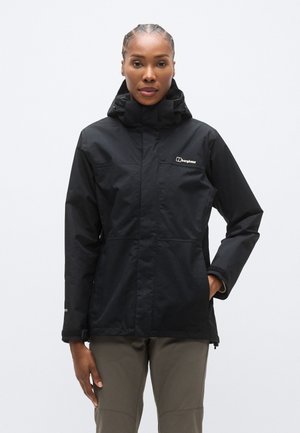 Sort vandtæt jakke med hætte, udstyret med en lynlås foran og to sidelommer. Fremstillet af slidstærkt materiale; har et logo på brystet.