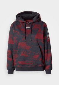 Sweat à capuche gris foncé avec un motif abstrait rouge. Comprend une poche avant, une capuche avec cordon de serrage, et un logo sur la poitrine.