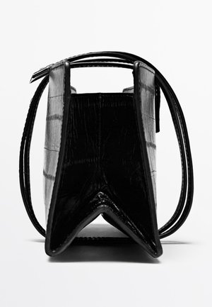 Zwarte faux krokodillenlederen tas met een gestructureerd ontwerp, driehoekige basis en twee dunne handvatten. Textuur oppervlak met een glanzende afwerking.