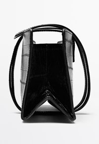 Zwarte faux krokodillenlederen tas met een gestructureerd ontwerp, driehoekige basis en twee dunne handvatten. Textuur oppervlak met een glanzende afwerking.