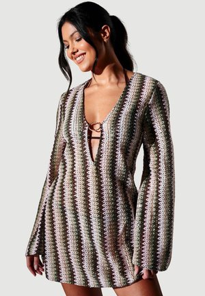 Multifarvet skiftkjole med dyb V-udskæring, der har et zigzag-mønster i grøn, brun og hvid samt lange ærmer med udslåede manchetter.