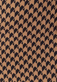 Hnedá tkanina s opakujúcim sa čiernym geometrickým vzorom, ktorý obsahuje trojuholníky a šípy. Textúra vyzerá hladko a tkané.
