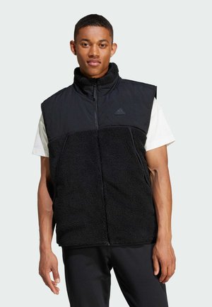 Chaleco negro sin mangas con cierre de cremallera, que presenta un cuerpo de forro polar texturizado y una parte superior de tela suave, mostrando el logo de Adidas en el pecho.