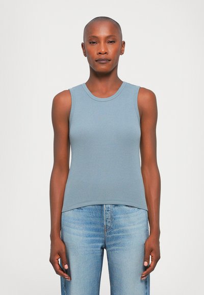 Débardeur côtelé bleu clair avec un col rond et une coupe ajustée, associé à un jean bleu clair, créant une tenue décontractée et coordonnée.