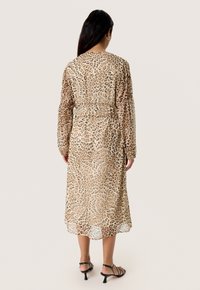 Leopardprint indpakningskjole i let stof med lange ærmer, en snøret talje og svajende kant. Farvepalet: beige og brun.