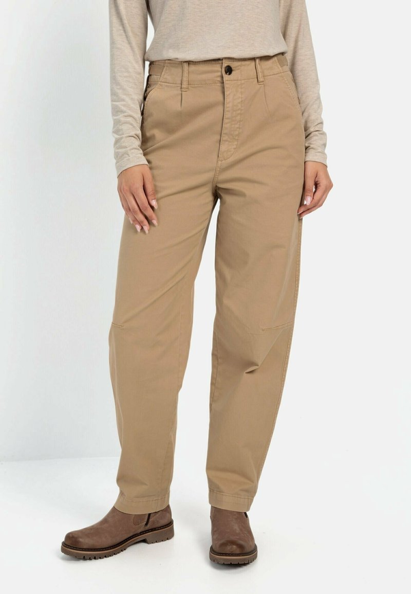 Pantalon beige taille haute à jambe droite, porté avec un haut beige à manches longues et des bottines marron, montré de la taille aux pieds.