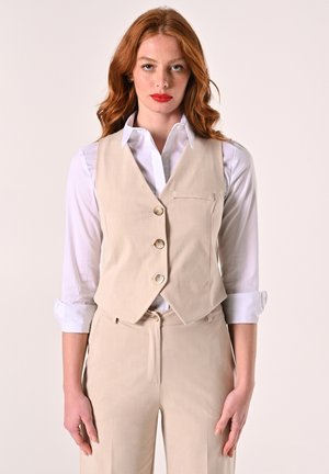 Beige tailored vest with three buttons, a small pocket on the left, paired with a white collared shirt. Smooth fabric and fitted design.