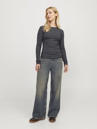 Mørkegrå langermet topp med en tettsittende design, parret med vide lyseblå jeans. Jeansene har en lett falming og en klassisk snitt.