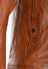 Bruine leren jas met een gladde textuur, voorzien van een zijzak met een zwarte drukknoop en zichtbare stikseldetails.