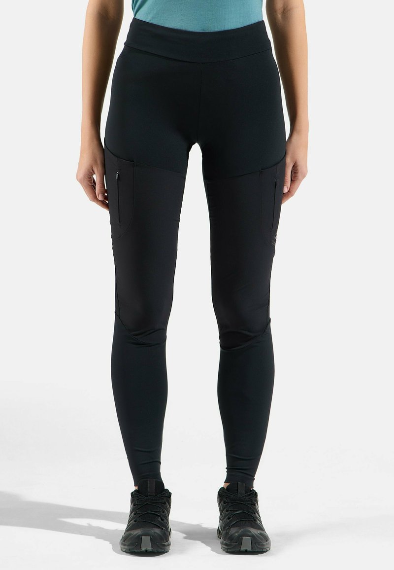 Leggings noirs extensibles avec une taille haute, des poches latérales et une coupe ajustée. Le tissu semble lisse avec une texture subtile.