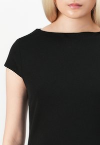 Fekete, rövid ujjas ruha sima textúrával, csónaknyakkal és testhezálló szabással. Minimalista dizájn, látható minták vagy kiegészítők nélkül.