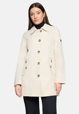 Beiger Mantel mittlerer Länge mit Kragen, sechs großen Knöpfen und zwei Seitentaschen. Hergestellt aus glattem Stoff mit lockerem Schnitt. Dezente Nähte setzen Akzente.