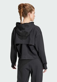 Zwarte cropped hoodie met een gelaagd ontwerp, voorzien van een ruime capuchon, lange mouwen en textiel met structuur. De achterkant toont uitsparingen ter hoogte van de taille.