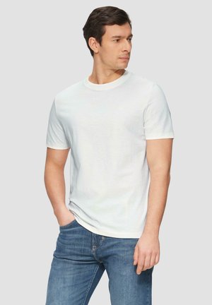 Witte T-shirt met korte mouwen en een ronde hals. Gemaakt van gladde stof. Draagt bij blauwe denim jeans. Eenvoudig ontwerp zonder opvallende logo's.