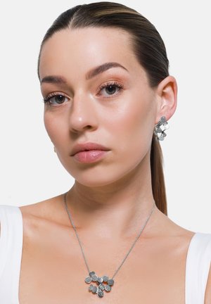 Set di gioielli in argento con pendenti circolari testurizzati su orecchini e collana, con una semplice catena d'argento e un design audace a strati.