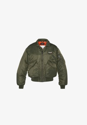 Olīvzaļš bumbieru jaka ar rāvējslēdzēju priekšā, divām priekšējām kabatām un iekšējo oranžo oderi. Iekļauj ribotās aproces un pufu uz krūtīm.