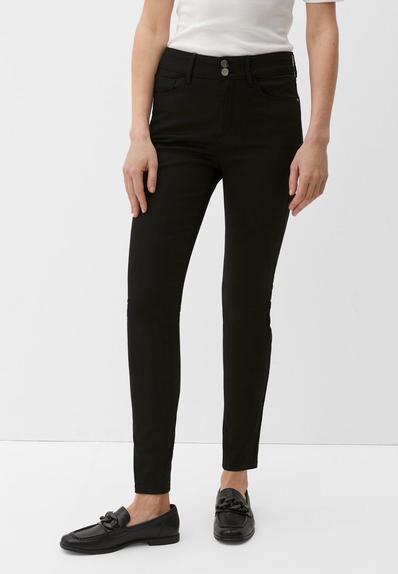 Jean skinny noir en matière extensible, avec une taille mi-haute, deux poches avant et deux poches arrière, fermeture par bouton.