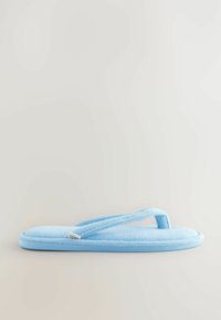 Flip-flop en peluche bleu clair avec une tige en tissu doux et une semelle plate. Présente une fine lanière entre les orteils et une étiquette logo sur le côté.