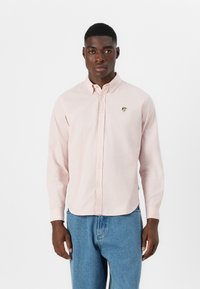 Light pink button-up shirt made of cotton with long sleeves and a curved hemline; features a small embroidered logo on the chest.