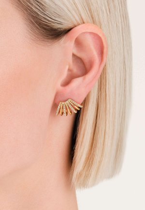 Pendientes de oro con un diseño ondulado, adornados con pequeños rhinestones transparentes. Los pendientes tienen una apariencia escultural y estratificada.