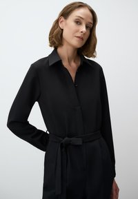 Zwarte overhemd met knoopsluiting, gemaakt van gladde stof, met een kraag, lange mouwen en een gestrikte tailleafwerking, die een slanke silhoe top weergeeft.