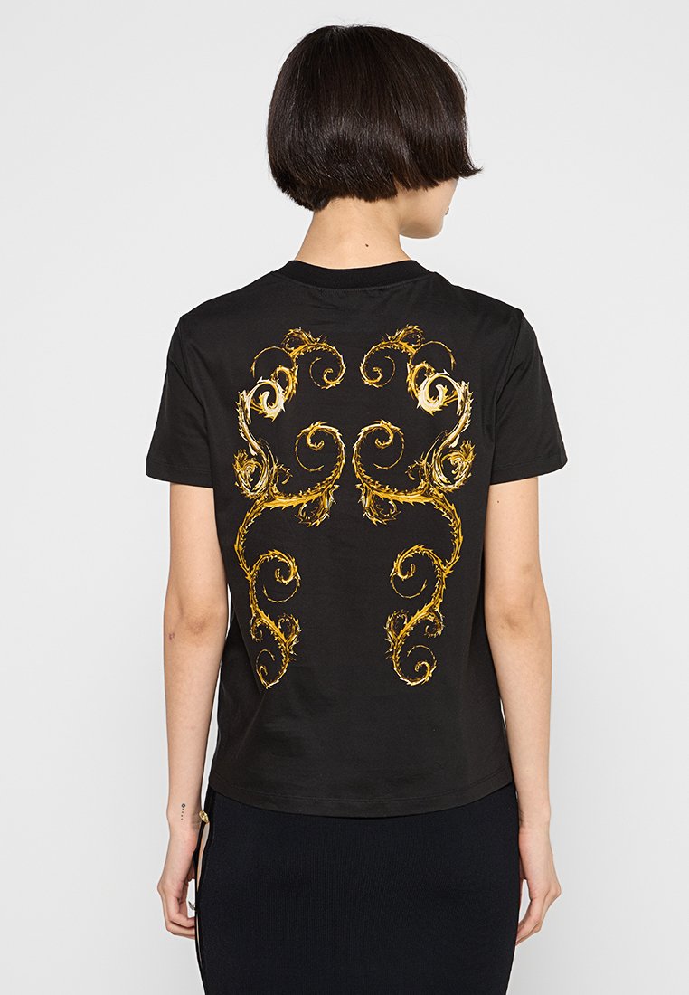 T-shirt noir avec des motifs en swirl dorés complexes dans le dos, manches courtes et col rond classique. Tissu en coton lisse.
