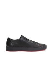Zapatillas de cuero negro con punta redonda, suela plana y detalles en rojo. Las características incluyen un diseño con cordones y costuras laterales en contraste.