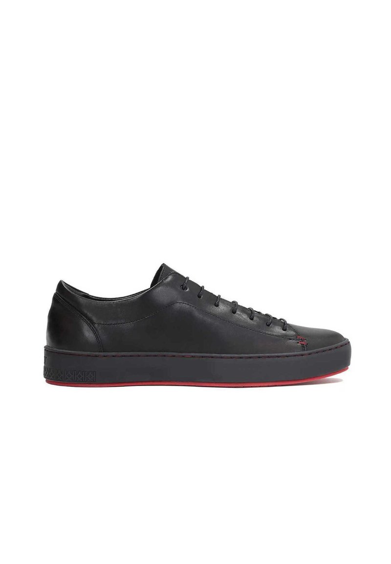 Zapatillas de cuero negro con punta redonda, suela plana y detalles en rojo. Las características incluyen un diseño con cordones y costuras laterales en contraste.