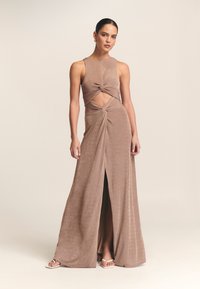 Długa, bezrękawnikowa brązowa sukienka wykonana z miękkiego materiału, z skręconym fasonem wycięcia w talii i rozcięciem do połowy uda.