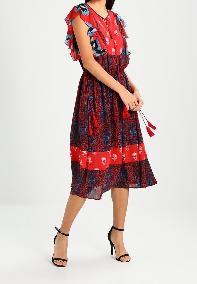 Rot-blau gemustertes Kleid mit Rüschenschüppen, tailliertem Bund und Quasten. Fließender Stoff in Midi-Länge mit gestuften Saumdetails.