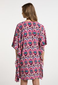 Vibranten kimono-stil pokrivalo v rožnati, zeleni in modri vzorec. Ohlapen kroj, kratki rokavi in mehak material s tekočim dizajnom.