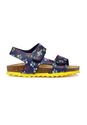 Sandalo per bambini blu navy con fantasie di aerei multicolori, soletta in sughero, due cinturini regolabili e suola gialla con texture.