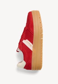 Baskets en daim rouge avec une touche beige et une semelle en caoutchouc gomme, dotées d'un col rembourré, de surpiqûres surélevées et de lacets ronds.