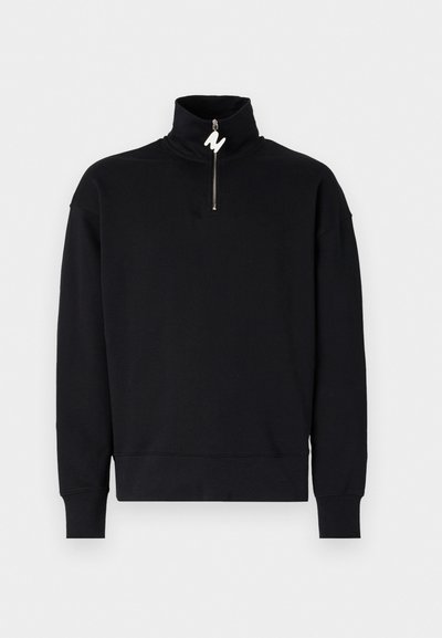 Sudadera negra con collar alto y cierre de media cremallera. Tejido suave, corte relajado y puños acanalados. Sin estampados ni acentos adicionales.