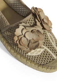 Beige espadrille met een textured mesh bovenkant, versierd met twee lichte leren bloemen en een gevlochten jute zool.