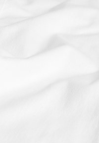 Tela blanca suave con una textura lisa, que presenta líneas sutiles del tejido, creando pliegues y ondas suaves en todo su superficie.