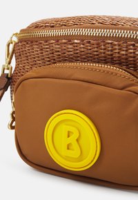 Borsa intrecciata marrone con una cerniera dorata, dotata di una tasca frontale marrone scuro e un logo rotondo giallo con una "B" al centro.