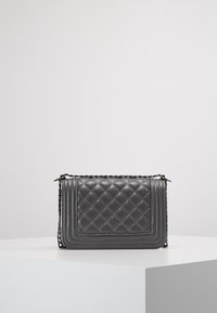 Šedá prošívaná kožená kabelka přes rameno s řetízkovým popruhem, obdélníkového tvaru, s horní klopou a kontrastním prošitím.