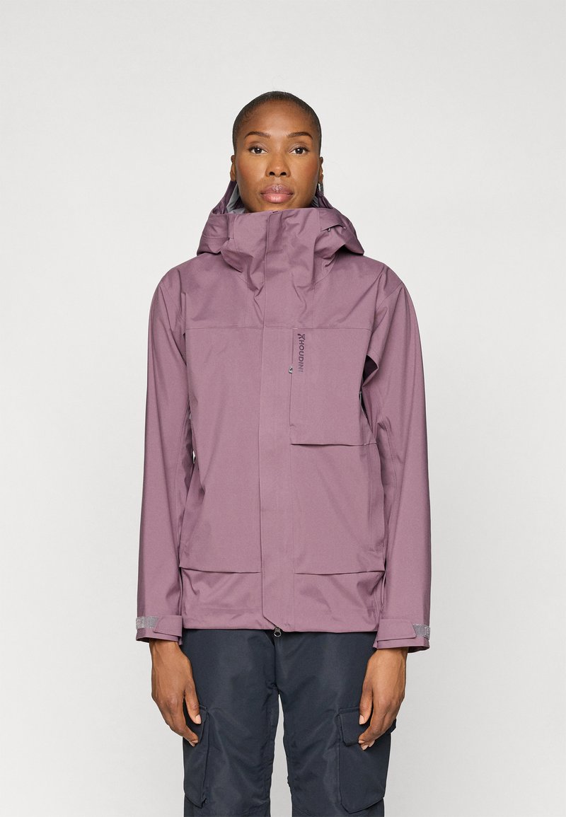 Chaqueta morada impermeable con alto cuello, capucha ajustable, bolsillo frontal y puños. Textura suave, diseño funcional para uso en exteriores.