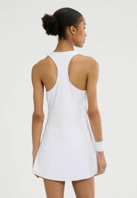 Biała sukienka sportowa z ramiączkami w stylu racerback, wykonana z gładkiego materiału. Posiada rozkloszowaną spódnicę i dopasowaną górną sylwetkę.