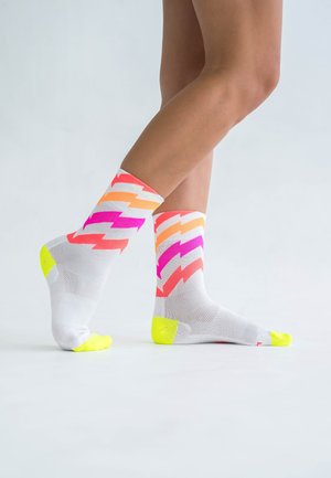 Bunte Socken mit einem weißen Grund und Zickzackmustern in rosa, orange und gelben Akzenten. Strukturierter Stoff mit leuchtend gelber Ferse und Spitze.