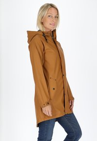 Impermeabile marrone con cappuccio, chiusura con zip e due tasche laterali. Caratterizzato da polsini elasticizzati e un design leggermente più lungo sul retro.