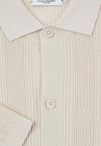 Polo shirt beige in maglia con un motivo testurizzato, polsini a coste e una patta con due bottoni. Etichetta con la scritta "PAOLO PECORA MILANO."